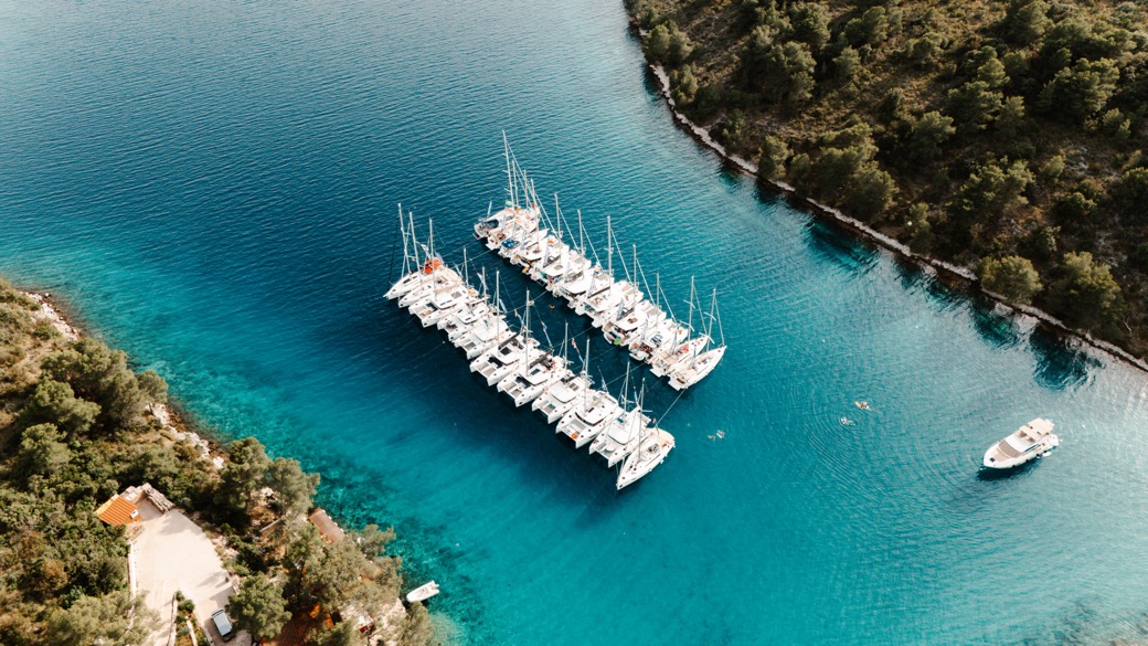 Yacht Week yachts rafted together in a turquoise Croatian bay, seen from above